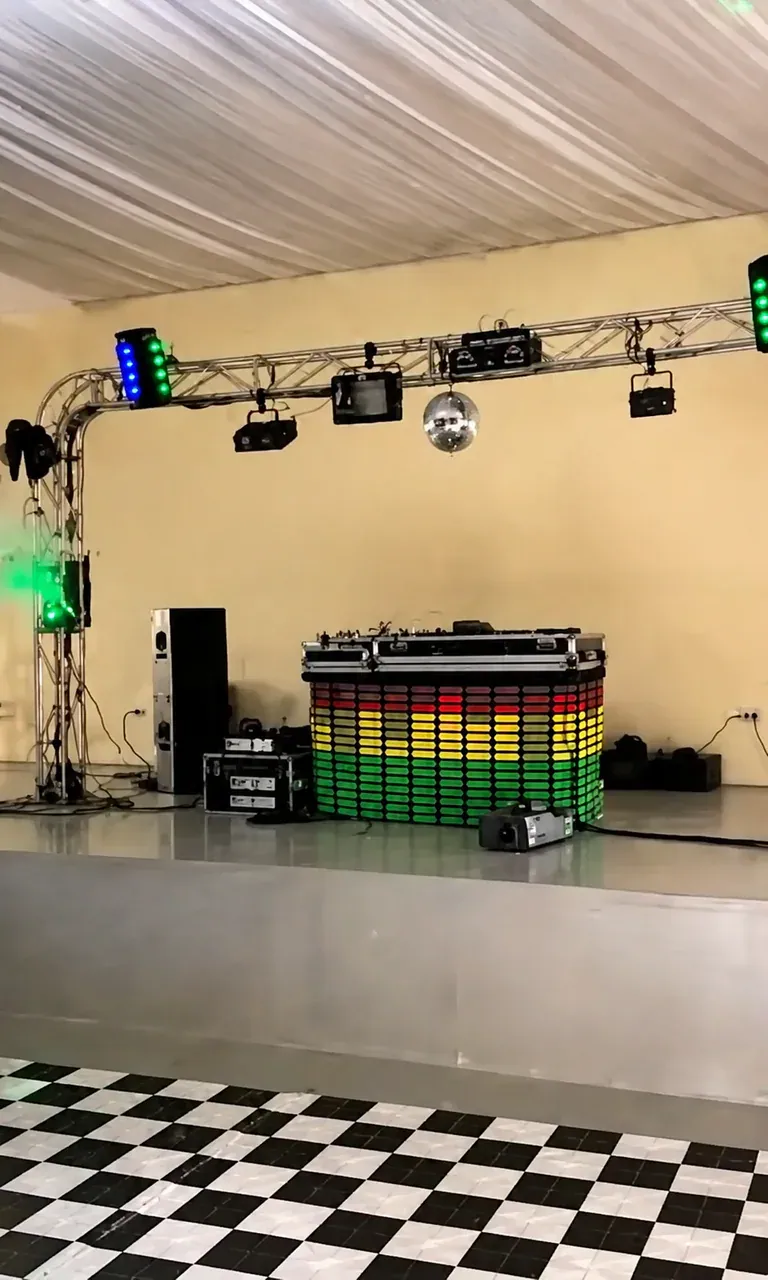 Cabine de DJ com treliça e iluminação. Montagem de cabine iluminada, treliça curva, caixas de som e efeitos para uma pista de dança compacta.