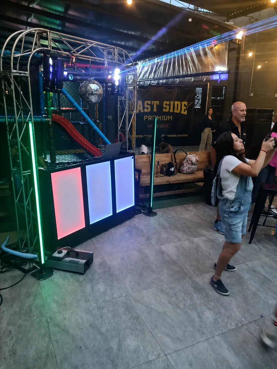 Estrutura de DJ em espaço de entretenimento. Cabine com painéis de LED, treliça e iluminação instalada em ambiente descontraído para evento social.