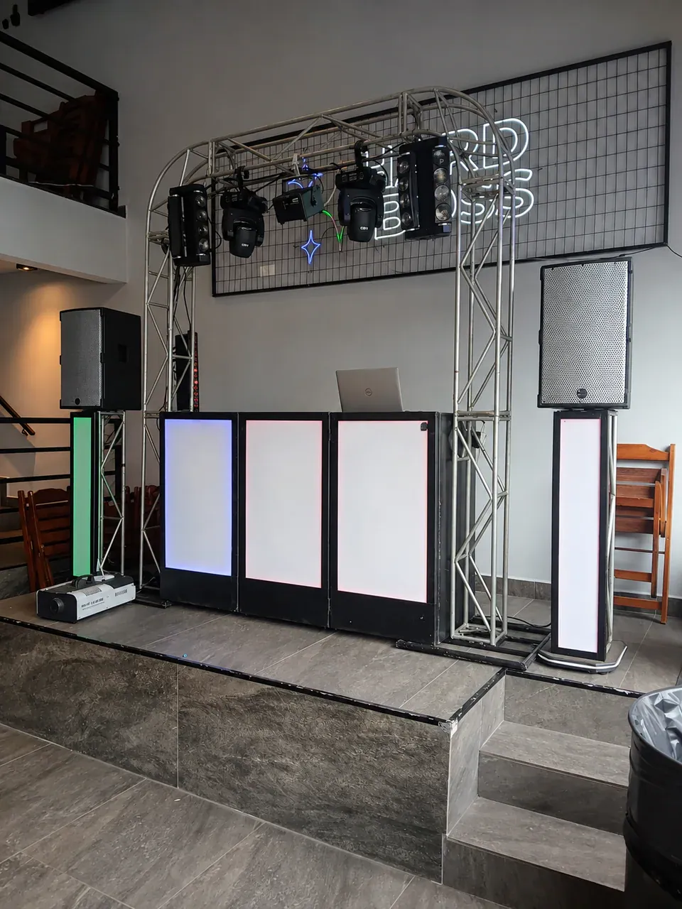 Cabine de DJ para salão moderno. Montagem organizada sobre palco, com iluminação integrada à cabine e sonorização posicionada nas laterais.
