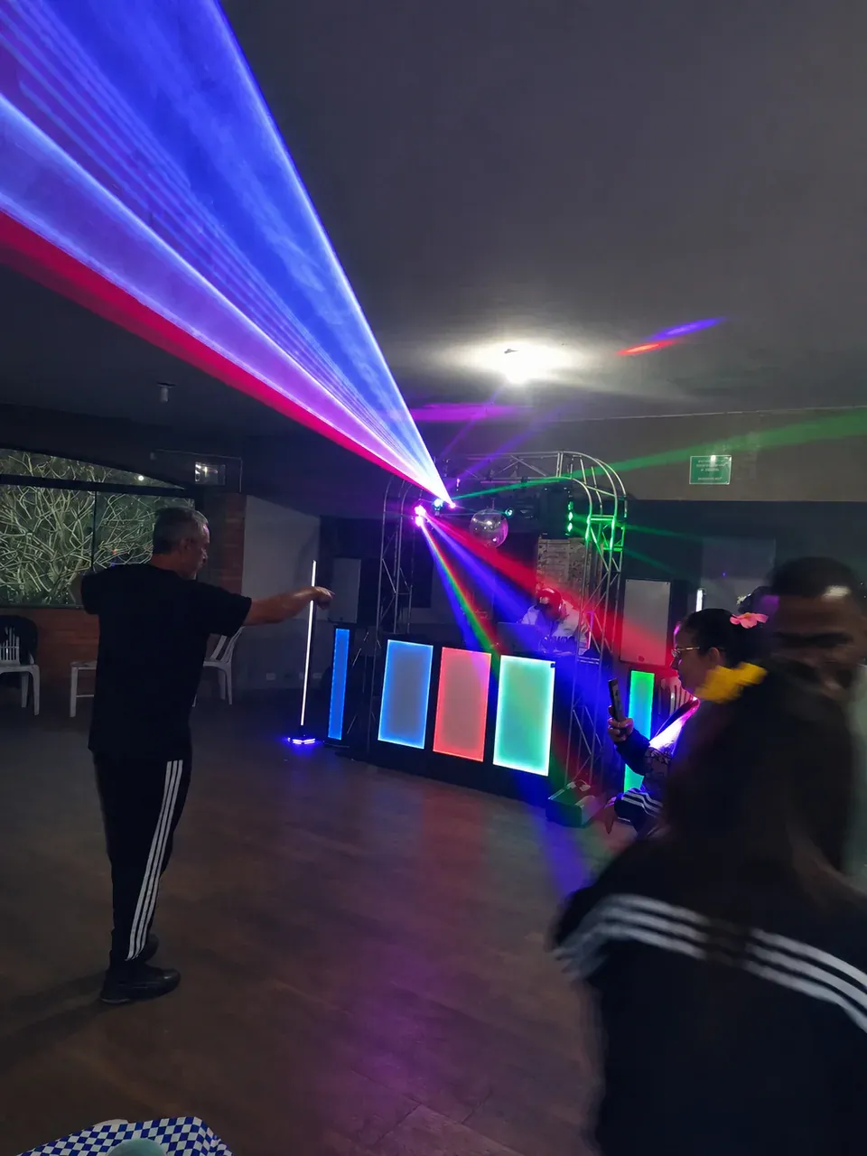 Atmosfera colorida em evento noturno. Convidados envolvidos por feixes coloridos enquanto a estrutura da CSOM transforma o salão em pista.