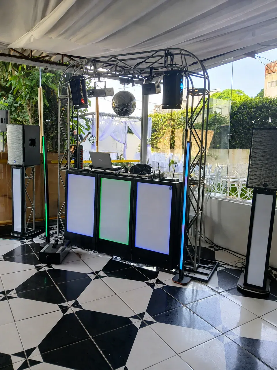 Cabine de DJ com iluminação e globo espelhado em área coberta.