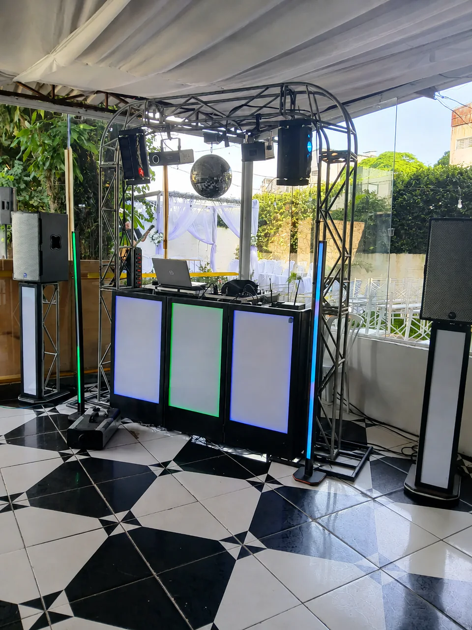 Cabine de DJ com iluminação e globo espelhado em área coberta.
