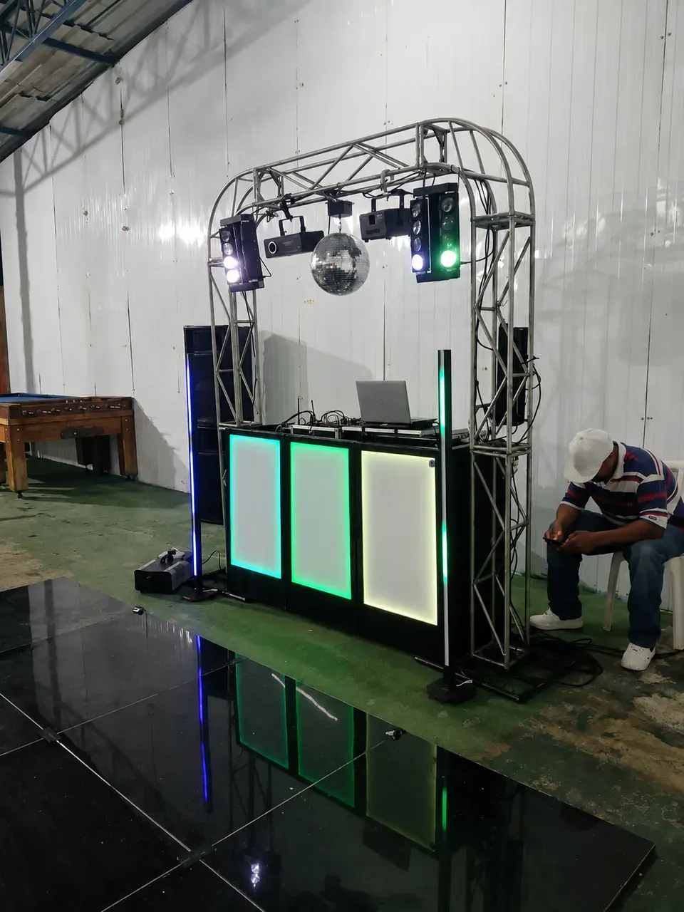 Estrutura com pista modular preta. Visão lateral da cabine e da pista de dança refletiva preparada para receber iluminação e convidados.