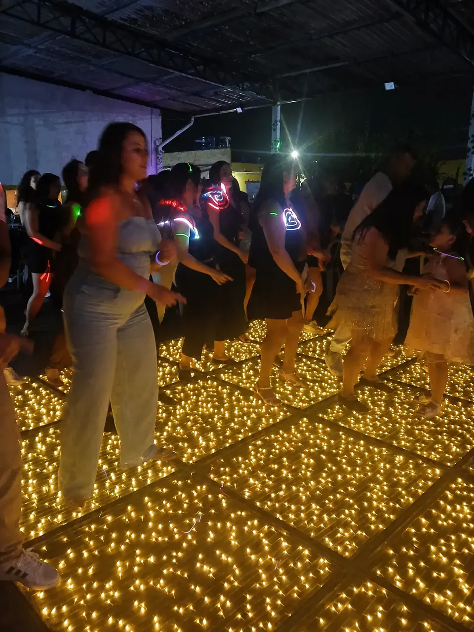 Guests wearing light-up accessories and dancing on an LED floor