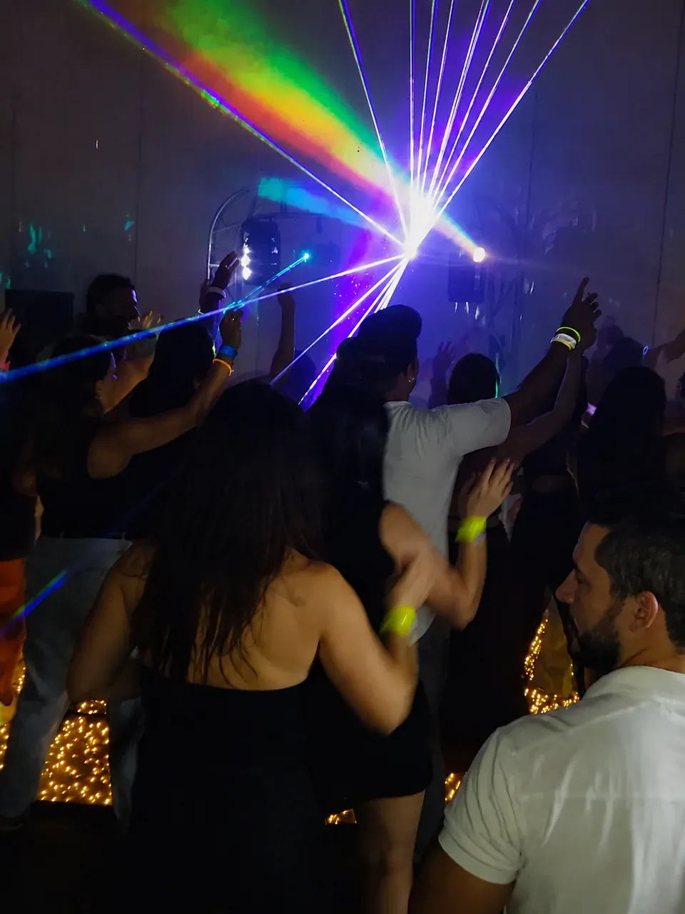 Convidados dançando sob feixes de luz colorida.