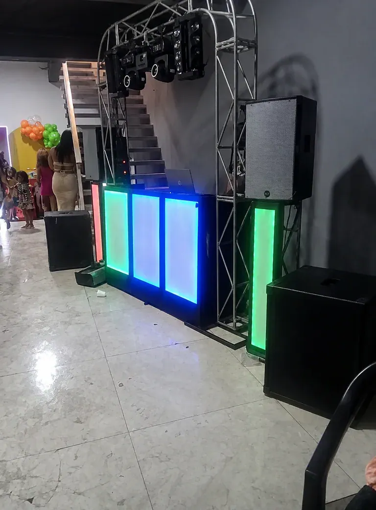 Som reforçado para festa familiar. Cabine iluminada, treliça e conjunto de caixas posicionados para cobrir o salão com clareza.