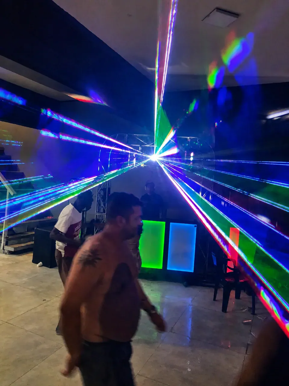 Explosão de cores com laser. Feixes verdes, azuis e violetas formam desenhos intensos sobre a pista durante a apresentação do DJ.